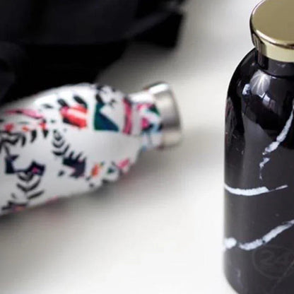 Two reusable water bottles, one with a colorful abstract pattern and one with a black marble design, on a white surface