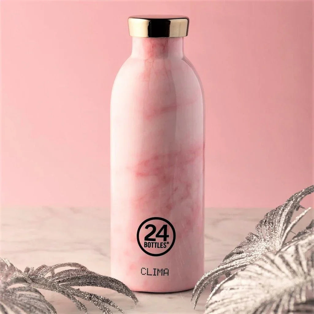 Pink marble insulated water bottle with gold cap on marble surface, decorative leaves.